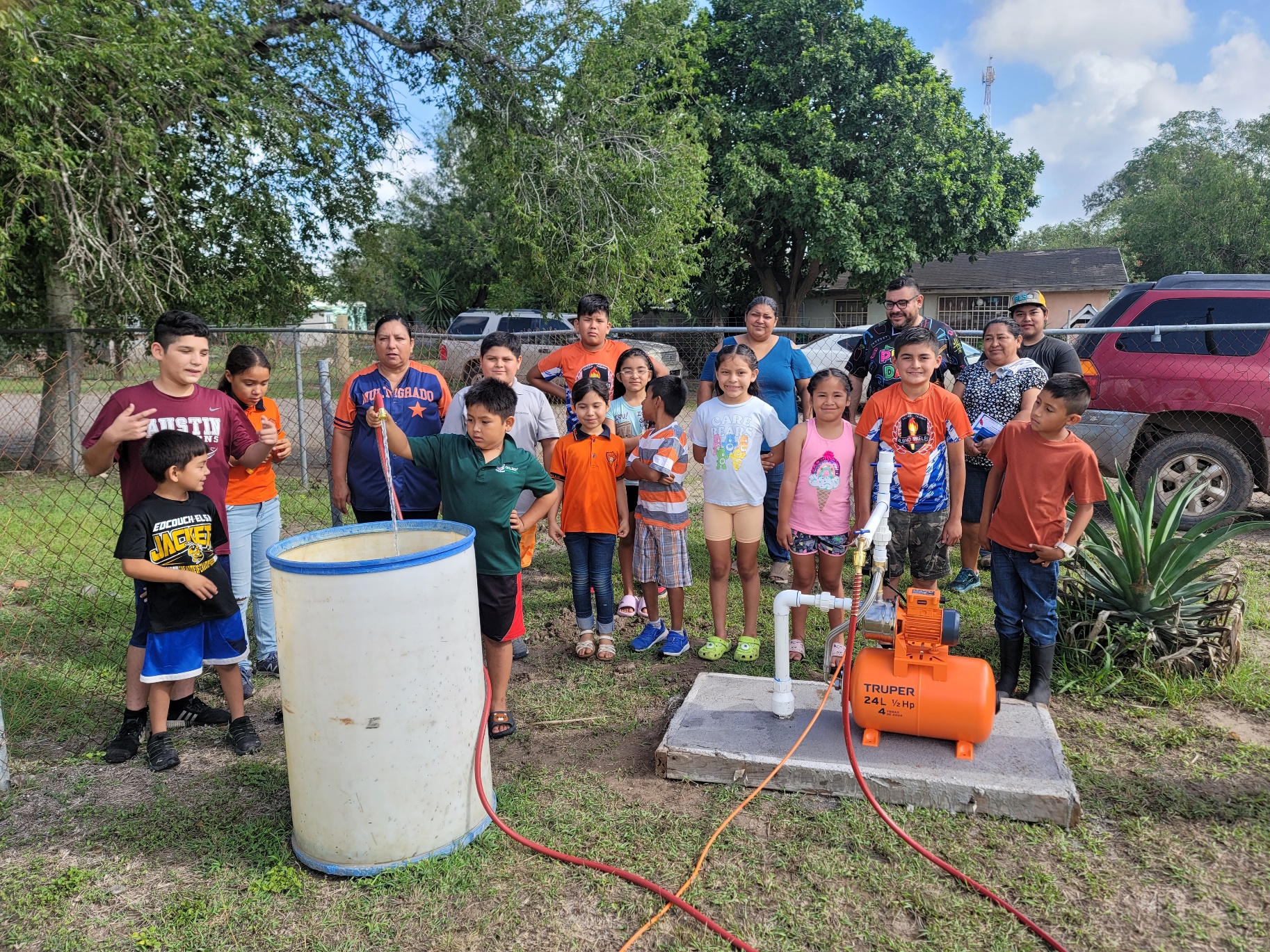 A group of children standing around a large white barrel
AI-generated content may be incorrect.